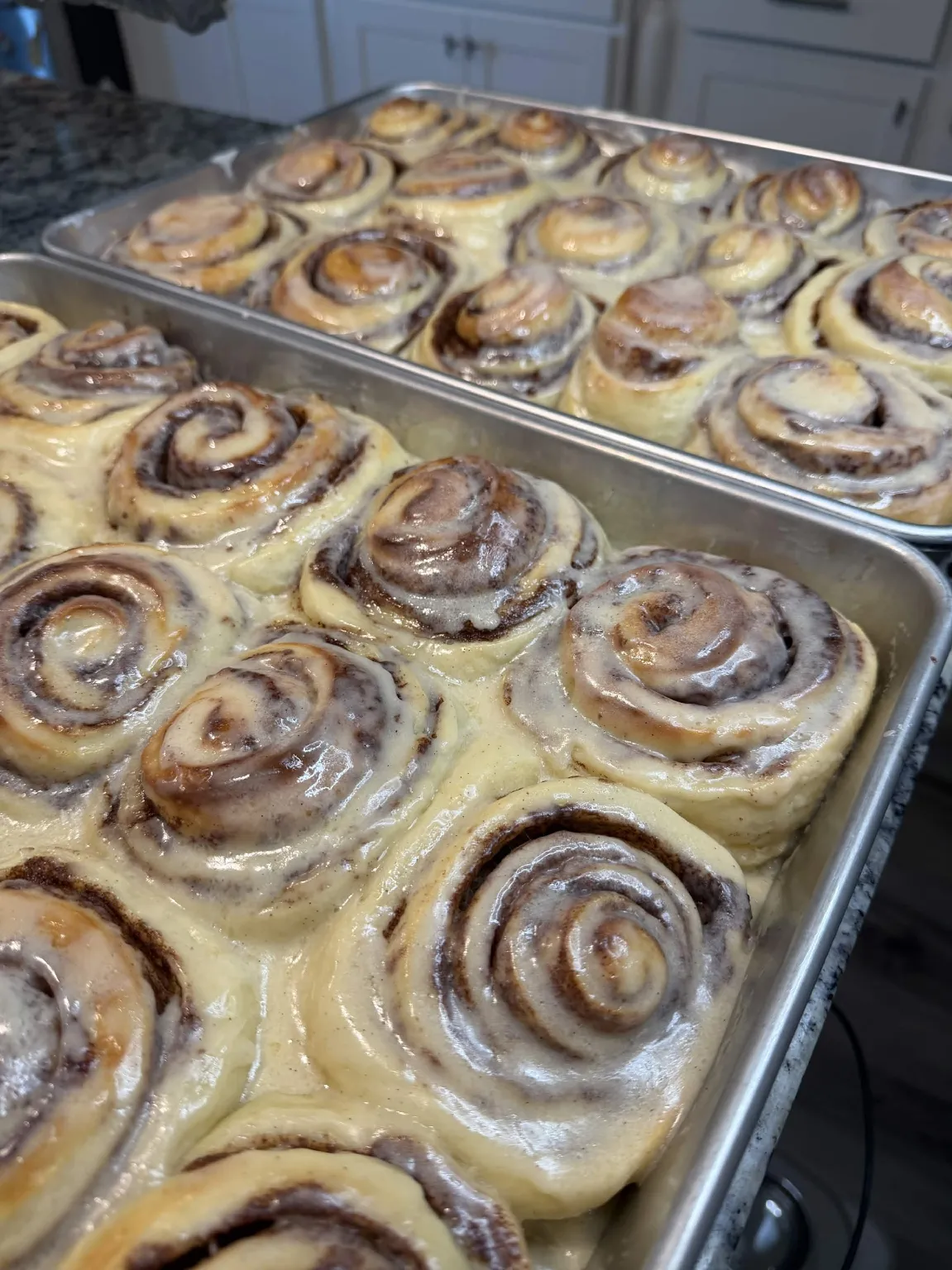 Trays of Rolling Dough Co. cinnamon rolls with icing in our kitchen
